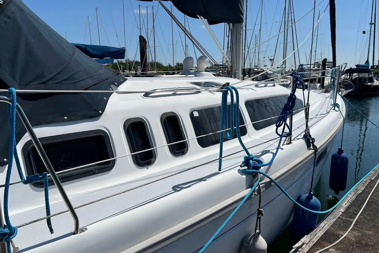 Sailboat Hunter 336, 1995 model, docked in marina with blue ropes and fenders.