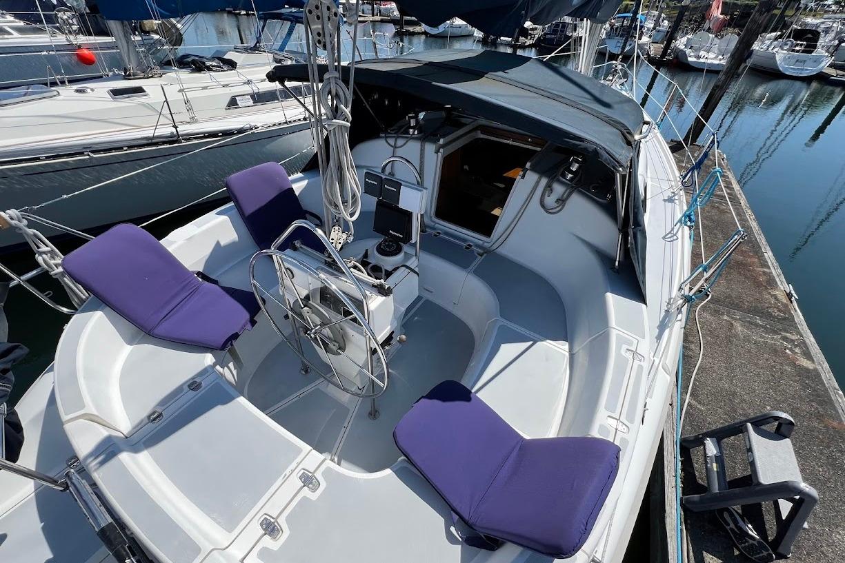 1995 Hunter 336 sailboat cockpit with purple cushions, docked in a marina.