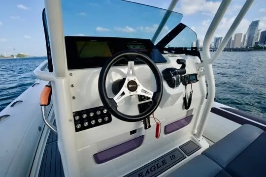  Yacht Photos Pics 2022 Brig Eagle 10 boat dashboard with steering wheel, controls, and city skyline in background.