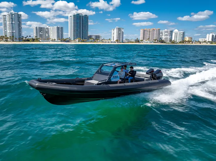  Yacht Photos Pics 2024 Goldfish X10 Scout boat cruising on blue ocean near city skyline.