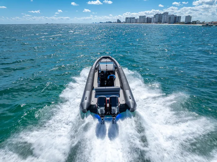  Yacht Photos Pics Goldfish X10 Scout 2024 boat speeding on ocean near city skyline.