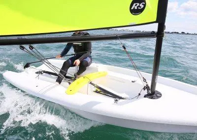 2024 RS Zest sailboat on the water with a sailor.