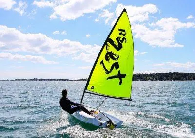 2024 RS Zest sailboat on open water under a sunny sky.