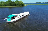 Custom 1958 boat cruising on a serene lake with lush green shoreline.