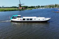 Vintage 1958 custom boat cruising on a scenic river with a windmill backdrop.