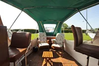 1958 custom boat interior with green canopy, wooden deck, and cushioned seating.