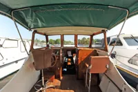 Interior of a vintage 1958 custom boat with wooden details and green canopy.