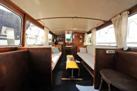 Interior of a vintage 1958 custom boat with wooden furnishings and white curtains.