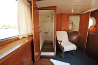 Vintage 1958 custom boat interior with wooden paneling, shower, and armchair.