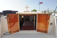 1958 custom boat cabin with open wooden doors, revealing interior and bed.