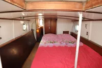 Cozy cabin interior of a 1958 custom boat with a red checkered bedspread.