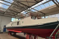 Custom 1958 boat in a workshop, elevated on stands, under a skylit roof.