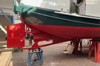 Custom 1958 boat under restoration in a workshop, featuring a red and green hull.