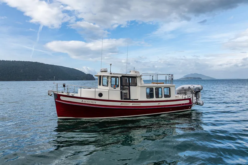 Artemis Yacht Photos Pics 1999 Nordic Tug 32 boat on calm water with scenic island backdrop.