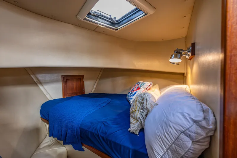 Artemis Yacht Photos Pics Cozy cabin interior of 1999 Nordic Tug 32 with blue bedding and overhead skylight.