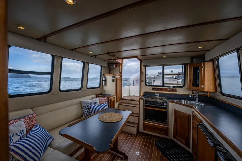 Artemis Yacht Photos Pics Interior of 1999 Nordic Tug 32 with dining area and kitchen, overlooking the sea.
