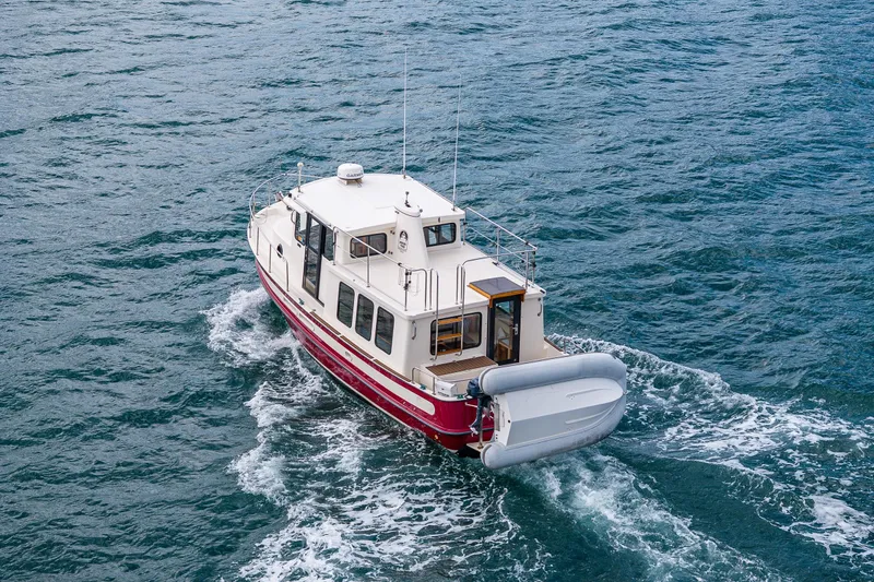 Artemis Yacht Photos Pics 1999 Nordic Tug 32 cruising on open water, featuring a red and white design.