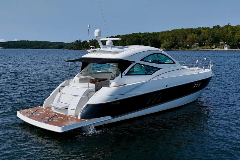  Yacht Photos Pics 2012 Cruisers Yachts 540 Sports Coupe on serene lake with lush green shoreline.