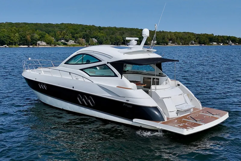  Yacht Photos Pics 2012 Cruisers Yachts 540 Sports Coupe on serene lake with lush shoreline.