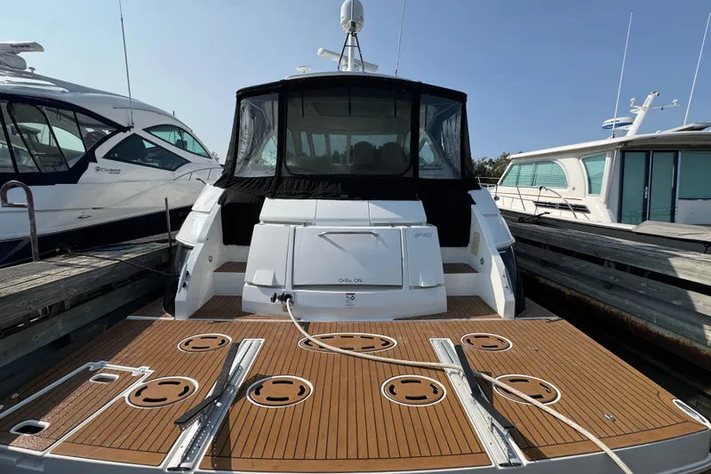  Yacht Photos Pics 2012 Cruisers Yachts 540 Sports Coupe docked, rear view with teak deck and black canopy.