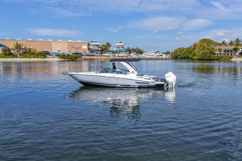  Yacht Photos Pics 2023 Monterey 305SS Super Sport boat cruising on a calm waterway under a clear blue sky.