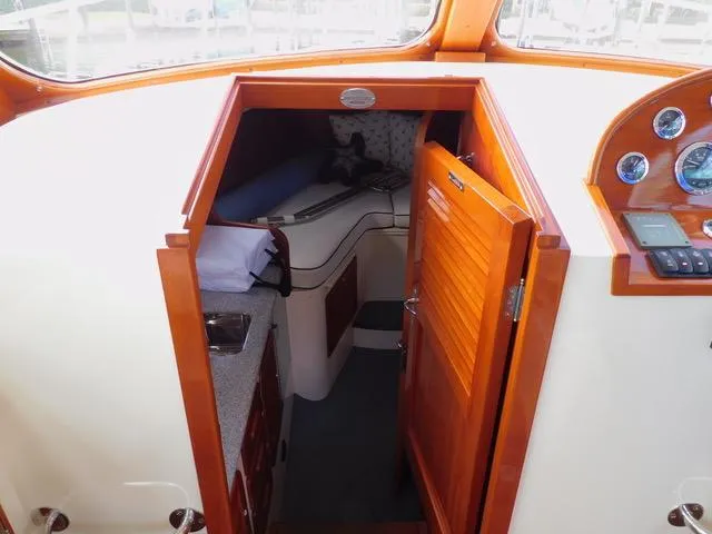  Yacht Photos Pics Interior cabin view of 2013 Hinckley T34 boat with wooden finishes and cozy sleeping area.