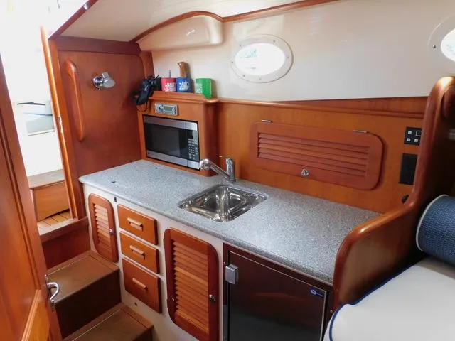  Yacht Photos Pics Hinckley T34 2013 yacht interior with kitchenette, featuring sink, microwave, and wooden cabinetry.