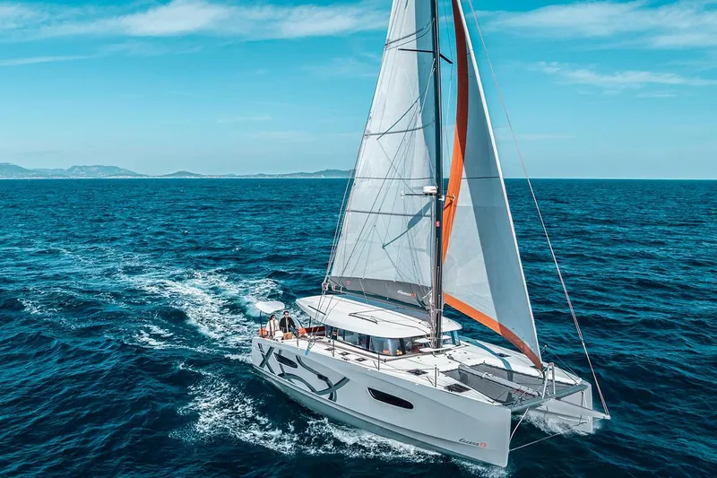  Yacht Photos Pics Manufacturer Provided Image: Sailing catamaran Excess 13, 2026 model, cruising on open sea under clear blue skies.