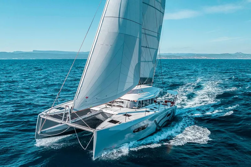 Yacht Photos Pics Manufacturer Provided Image: Sailing catamaran Excess 13, 2026 model, gliding on open sea under clear skies.