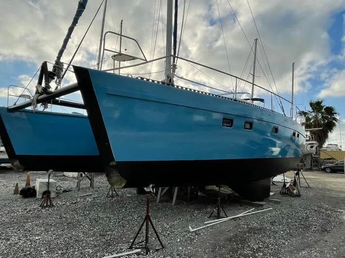 Freedom Yacht Photos Pics Blue 1993 Lagoon 42 catamaran on dry dock under cloudy sky.