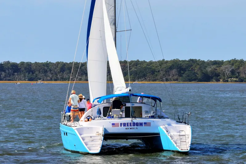 Freedom Yacht Photos Pics Lagoon 42 catamaran sailing on a calm lake, 1993 model, with people on deck.
