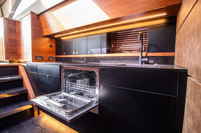  Yacht Photos Pics Luxurious yacht kitchen with open dishwasher, sleek wood and black finishes, Van der Heijden 2021.