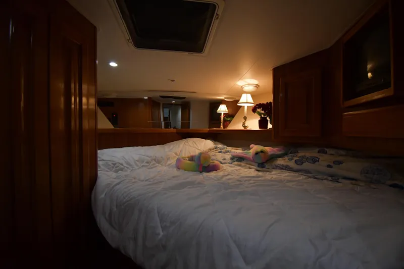 Your Rent's Due Yacht Photos Pics Cozy bedroom interior of 1996 Viking 50 Convertible yacht with plush bedding and warm lighting.