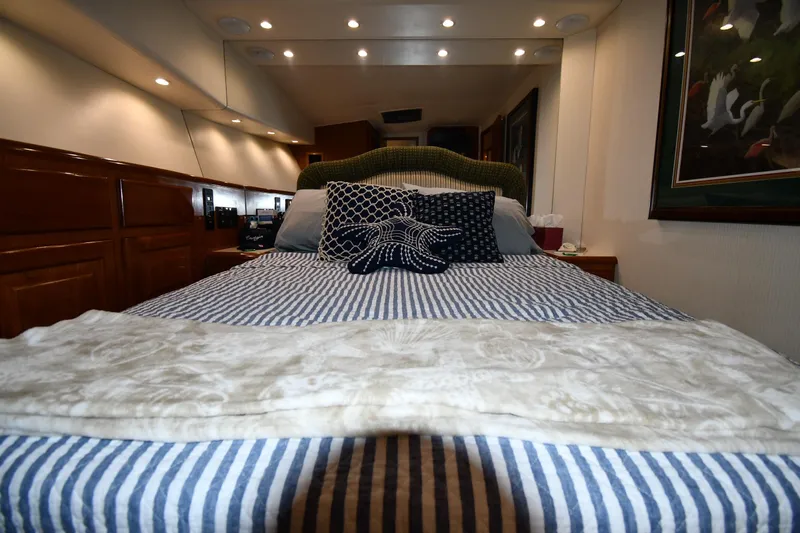 Your Rent's Due Yacht Photos Pics Cozy bedroom interior of 1996 Viking 50 Convertible yacht with striped bedding and decorative pillows.