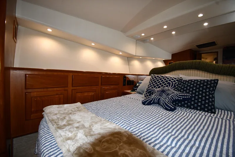 Your Rent's Due Yacht Photos Pics Luxurious bedroom interior of 1996 Viking 50 Convertible yacht with striped bedding and decorative pillows.