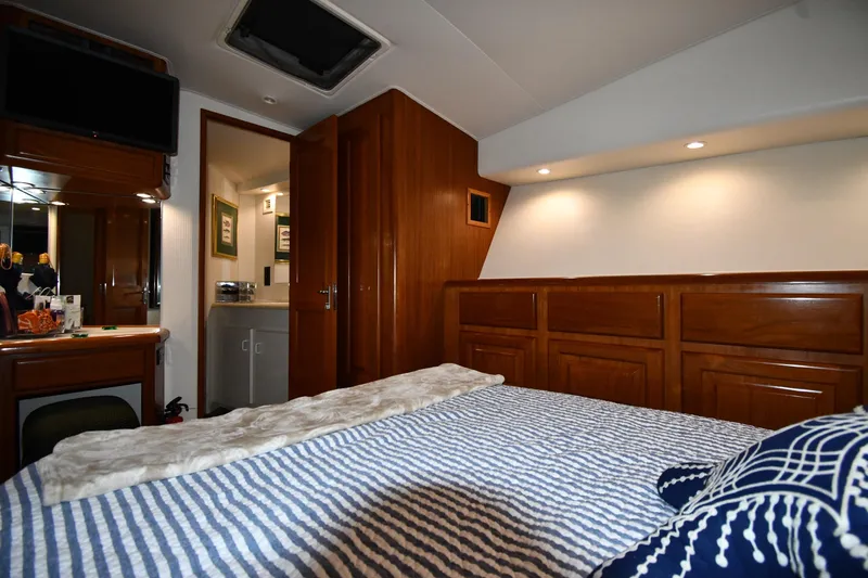 Your Rent's Due Yacht Photos Pics Luxurious cabin interior of 1996 Viking 50 Convertible yacht with wood paneling and cozy bedding.