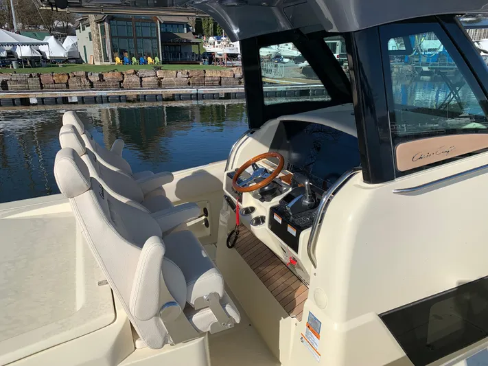 Yacht Photos Pics 2024 Chris-Craft Catalina 34 helm with plush seating and wooden steering wheel, dockside view.