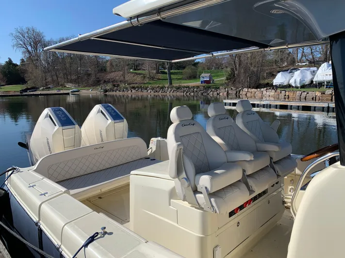  Yacht Photos Pics 2024 Chris-Craft Catalina 34 boat interior with luxurious seating and canopy, docked by a serene lake.