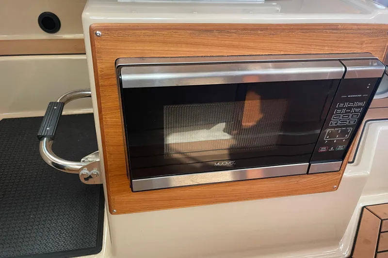  Yacht Photos Pics Microwave in 2019 Ranger Tugs R-27 boat interior, featuring wood paneling and stainless steel accents.