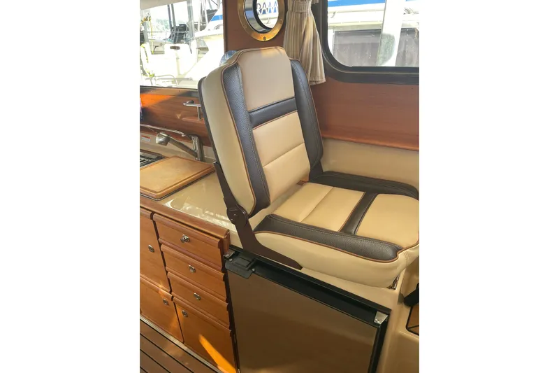  Yacht Photos Pics 2019 Ranger Tugs R-27 interior with beige and brown seating, wooden cabinetry, and window view.