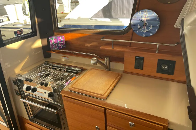  Yacht Photos Pics 2019 Ranger Tugs R-27 interior kitchen with stove, cutting board, and nautical clock.