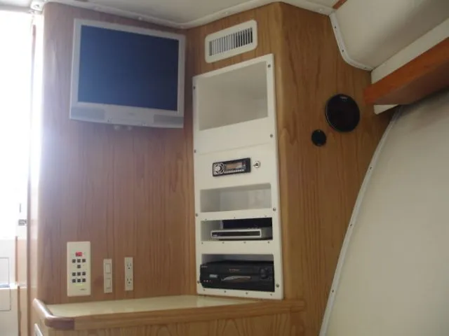 Bait's Factor Yacht Photos Pics Interior of 2002 Stolper 35 EXPRESS with TV and audio system on wooden panel.