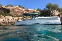 2023 Saxdor 270 GTO boat near rocky shoreline under clear blue sky.