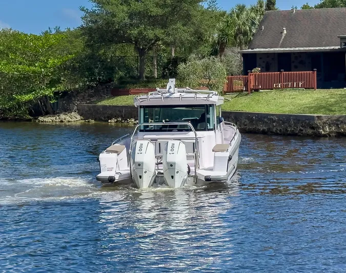  Yacht Photos Pics 2024 Axopar 37XC CROSS CABIN boat cruising on a scenic waterway.