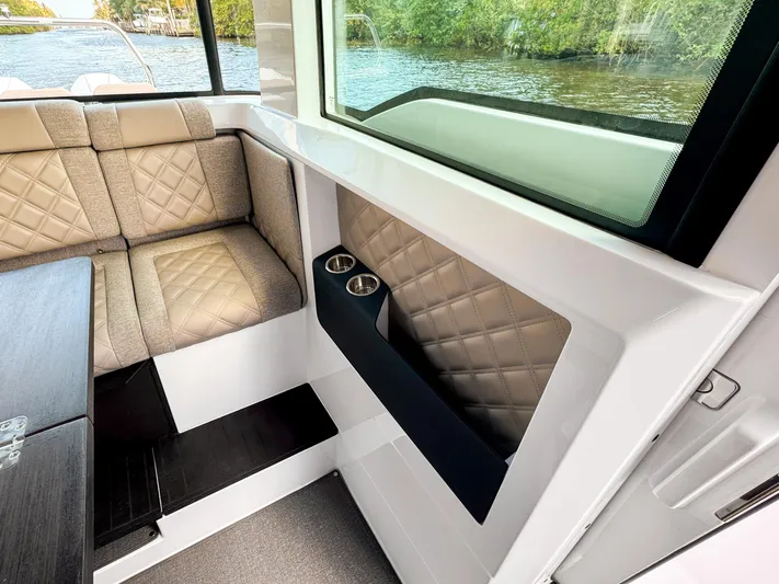  Yacht Photos Pics 2024 Axopar 37XC CROSS CABIN interior with quilted seating and cup holders by a window.