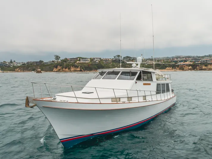 Vin Santo Yacht Photos Pics 1984 Vic Franck pilothouse yacht on the water near a coastal landscape.