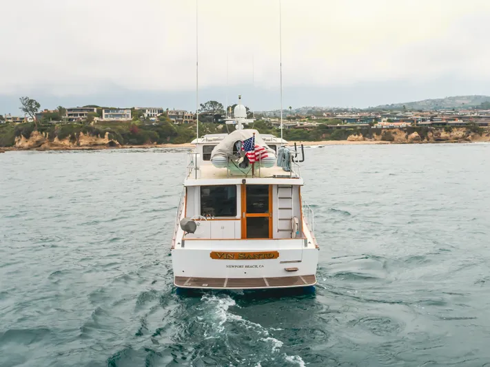 Vin Santo Yacht Photos Pics 1984 Vic Franck pilothouse yacht on ocean near coastal homes, American flag displayed.
