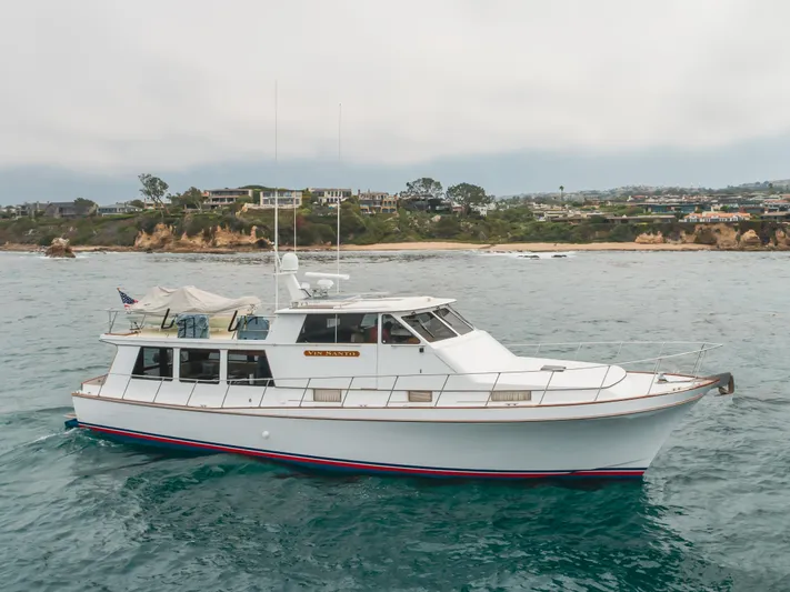 Vin Santo Yacht Photos Pics 1984 Vic Franck pilothouse yacht cruising near a scenic coastal landscape.