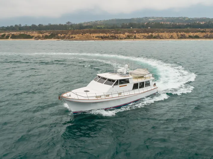 Vin Santo Yacht Photos Pics 1984 Vic Franck pilothouse yacht cruising near a scenic coastline.