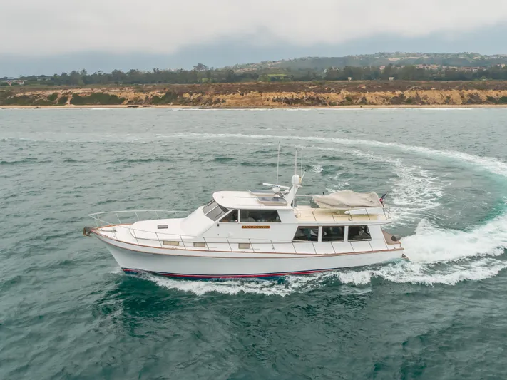 Vin Santo Yacht Photos Pics 1984 Vic Franck pilothouse yacht cruising on the ocean near a scenic coastline.